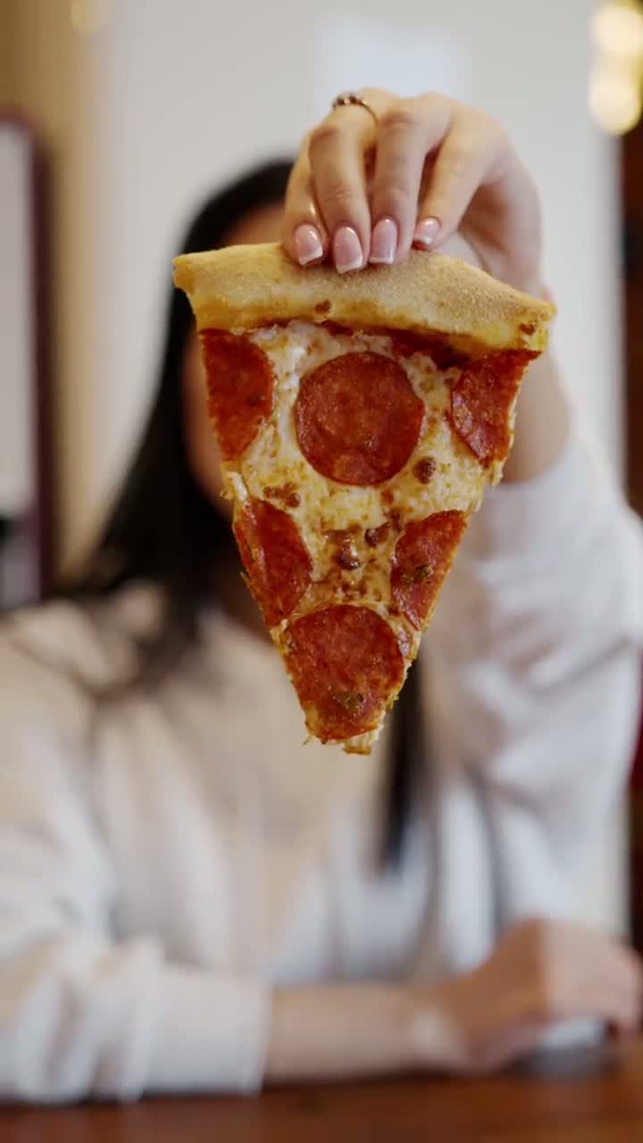 Creator holding up a slice of pizza to camera